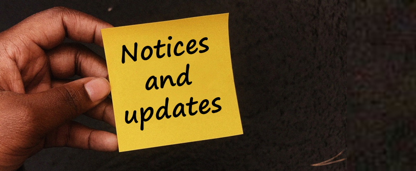 a hand holding a yellow post it note with notices and updates written on it