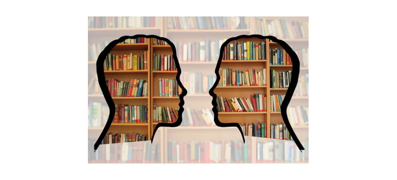 A silhouette of two heads looking at each other in front of a bookshelf.
