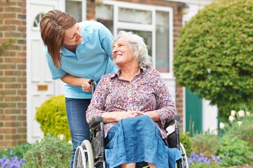 A carer and a woman in a wheelchair in the garden together